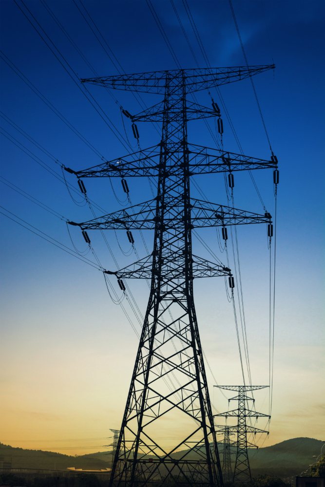 Transmission tower silhouetted against a blue dusk sky