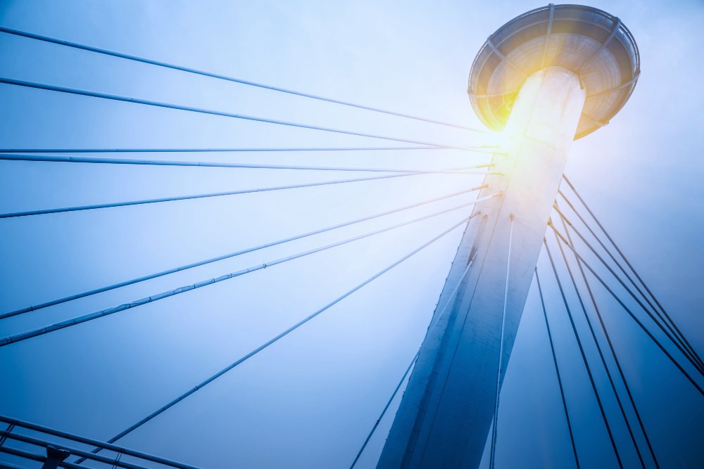 Modern cable-stayed tower lit by the sun against a blue sky
